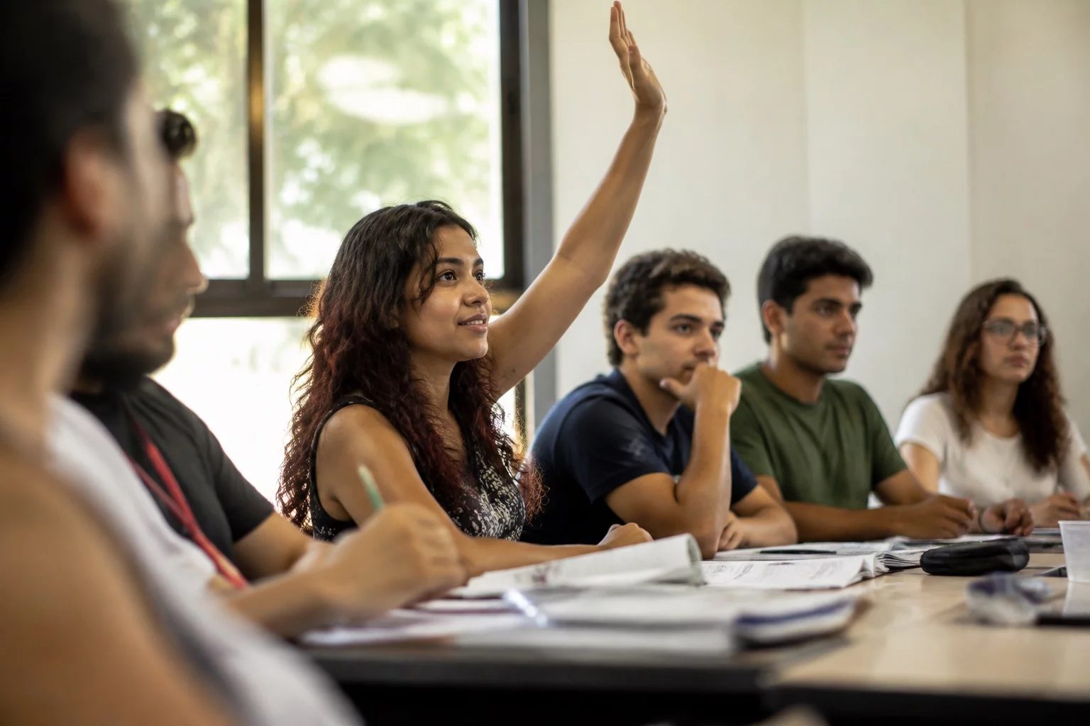 Estudante levantando a mão em uma mesa de seminário coberta de anotações